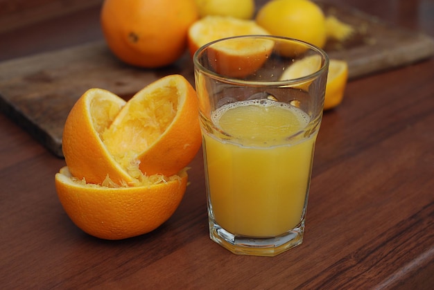 Jugo de naranja exprimido y frutas cítricas de naranjas frescas en mesa de madera rústica. Concepto de dieta y alimentos saludables