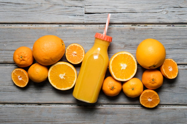 Jugo de naranja fresco en una botella con naranjas en un fondo de madera rústica