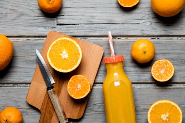 Jugo de naranja fresco en una botella con naranjas sobre un fondo rústico de madera