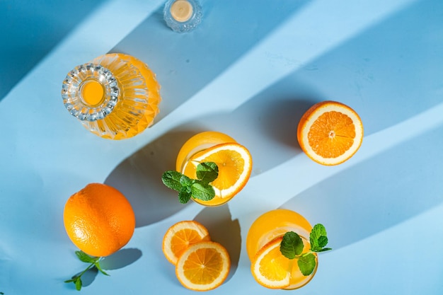 Jugo de naranja fresco con hielo en un vaso sobre un cóctel de naranja de fondo azul