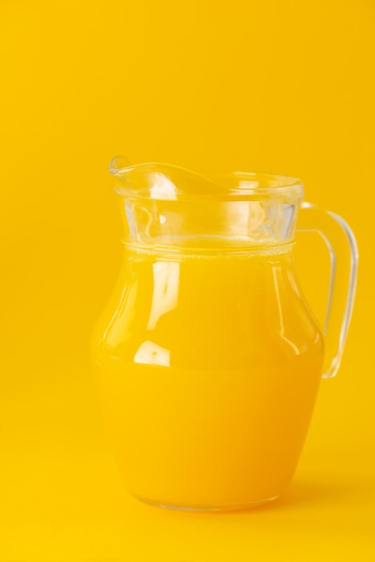 Jugo de naranja en una jarra sobre un fondo amarillo Enfoque selectivo