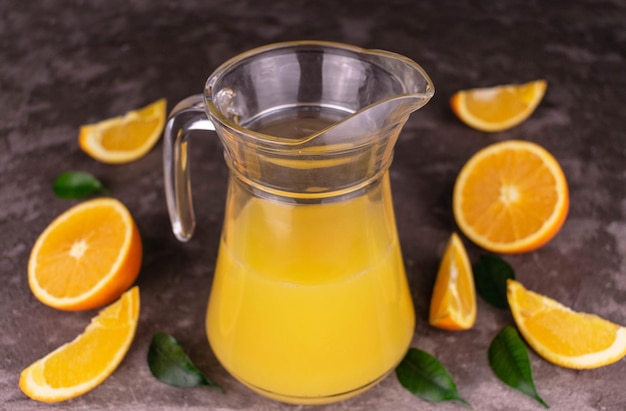 Jugo de naranja en una jarra sobre un fondo gris