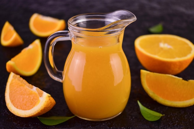 Jugo de naranja en una jarra de vidrio sobre un fondo negro.Primer plano.