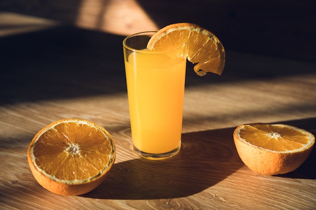 Jugo de naranja naranjas en rodajas sobre una mesa de madera