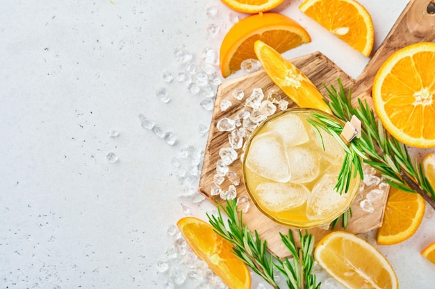 Jugo de naranja o cóctel con romero y naranja con hielo en vaso, limonada fría de verano