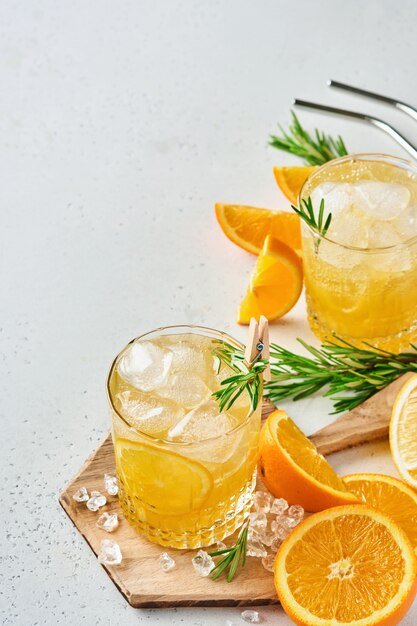 Jugo de naranja o cóctel con romero y naranja con hielo en vaso, limonada fría de verano