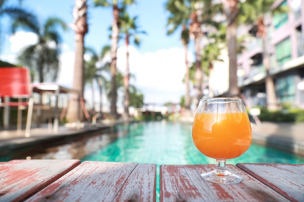 Jugo de naranja en la piscina con palmeras y espacio de copia