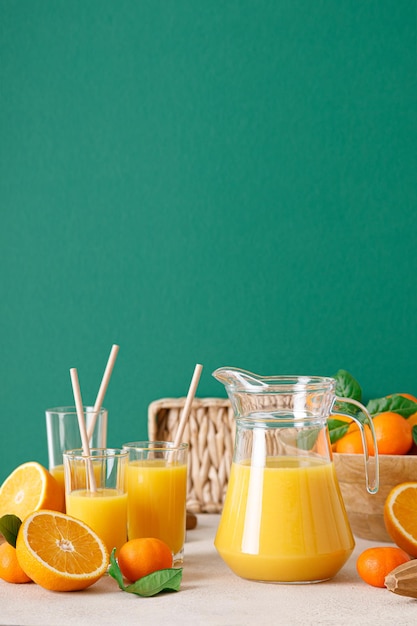 Jugo de naranja recién exprimido en una jarra de vidrio y frutas frescas con hojas bebida saludable concepto de vitamina c espacio de copia de vista frontal para un texto