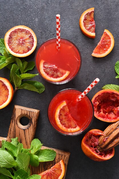 Jugo de naranja rojo con menta sobre una superficie de hormigón negro Bebida de verano