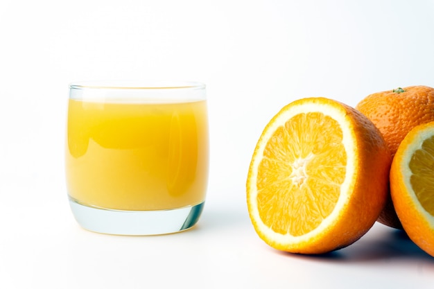 Jugo de naranja en una taza de vidrio transparente con naranjas frescas.