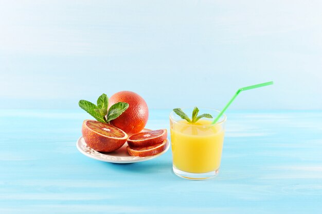 Jugo de naranja en vaso con menta y una pajita