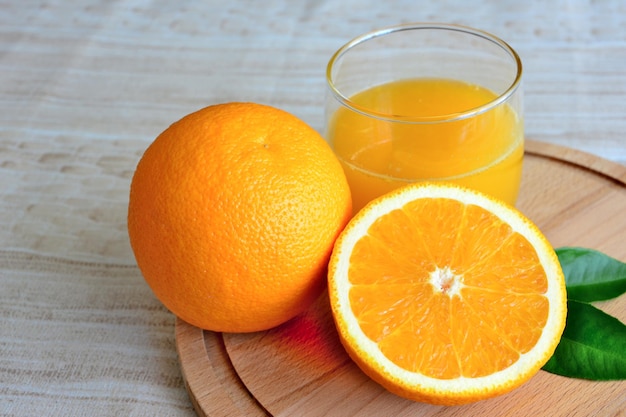 Jugo de naranja en vaso con la mitad de naranja aislado en tabla de cortar, macro