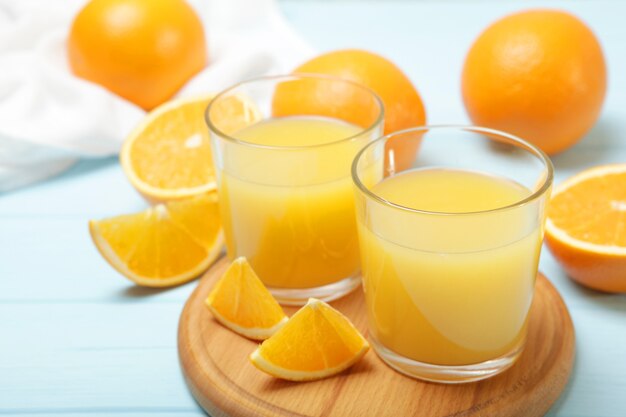 Jugo de naranja en un vaso de naranjas y rodajas de naranja sobre la mesa