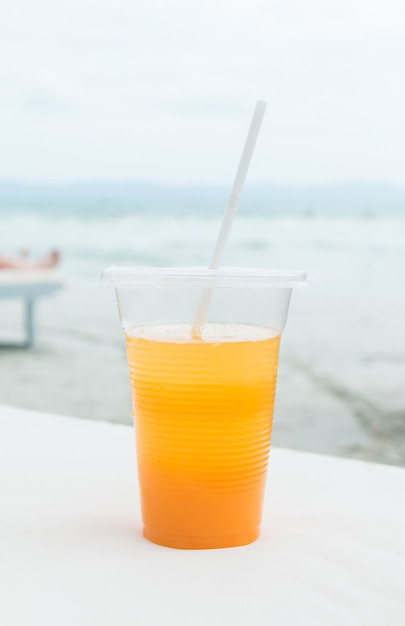 Jugo de naranja en un vaso en la playa