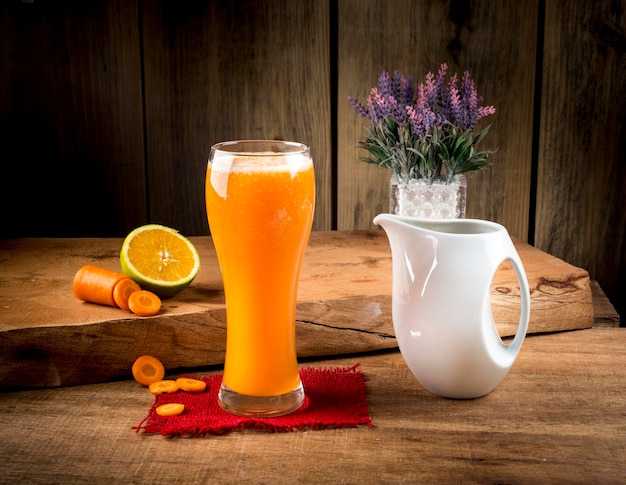 Jugo de naranja con zanahoria con rodajas de naranja y zanahoria sobre fondo de madera