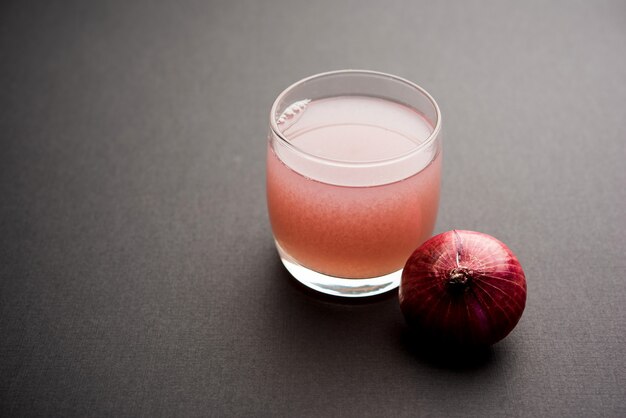 Jugo o almíbar de cebolla medicinal en un vaso con cebollas crudas. enfoque selectivo