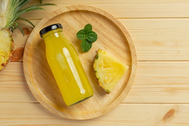 Jugo de piña en botella sobre superficie de madera