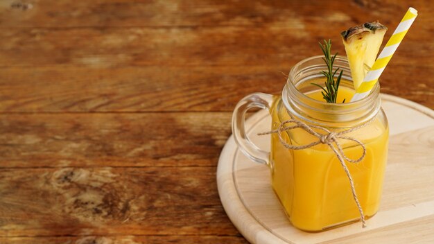 Jugo de piña en un frasco de vidrio, rodajas de piña decoran la bebida