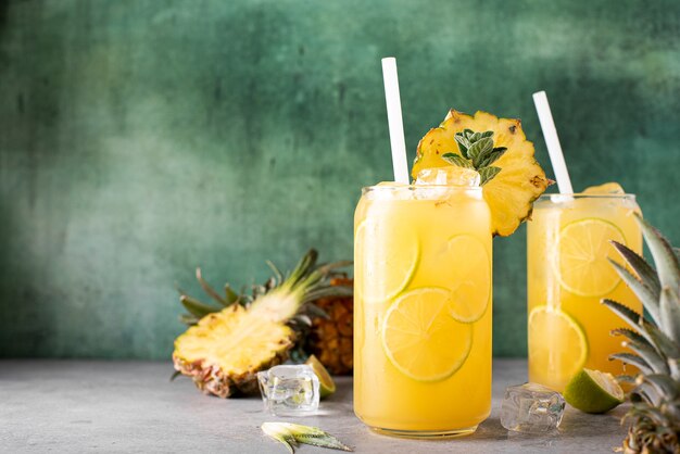 Jugo de piña recién exprimido con rodajas de limón y hielo en frascos de vidrio