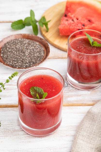 Jugo de sandía con semillas de chía y menta en vidrio sobre un fondo de madera blanca con tejido de lino. Concepto de bebida saludable. Vista lateral, de cerca.