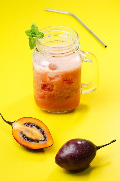 Jugo de tamarillo o berenjena holandesa con el nombre latino Solanum betaceum con un fondo amarillo.