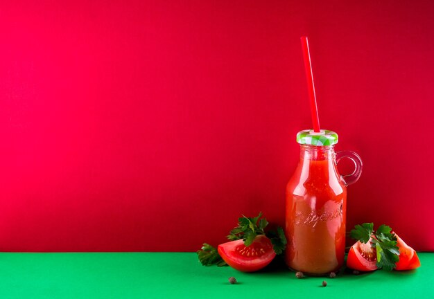 Jugo de tomate en la botella sobre fondo rojo. Bebida saludable. Espacio