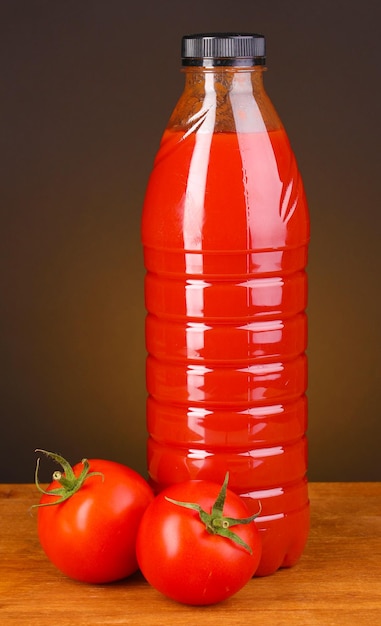 Jugo de tomate en botella sobre mesa de madera sobre fondo marrón