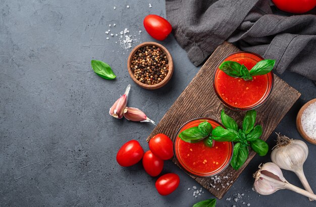 Jugo de tomate especias albahaca sal y ajo sobre un fondo azul grisáceo