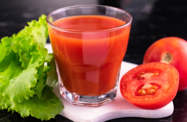 Jugo de tomate con especias en un vaso sobre un fondo negro.