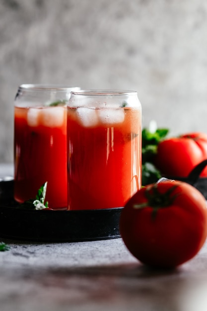 Jugo de tomate con hielo en un vaso sobre un fondo gris