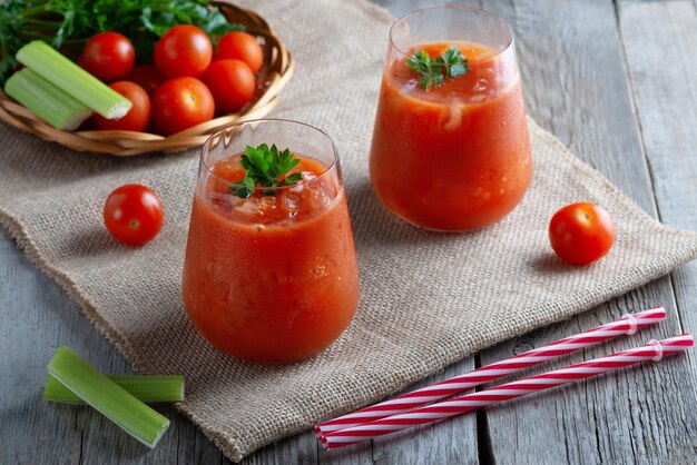 Jugo de tomate con hielo en vasos sobre una mesa antigua de madera