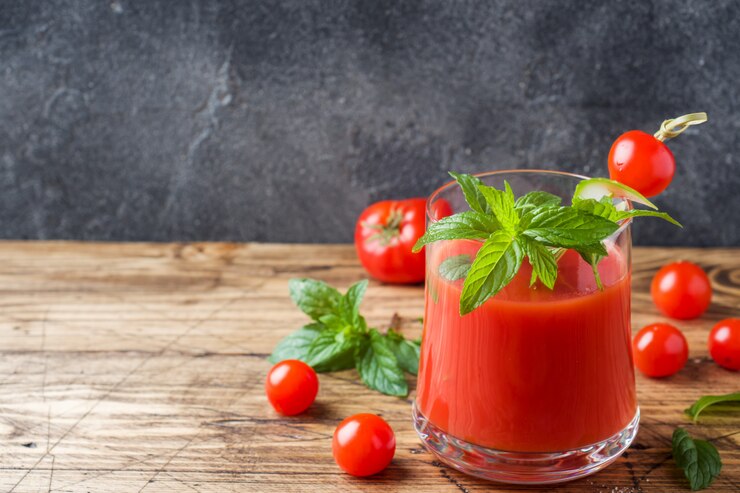 Jugo de tomate con menta en vidrio y tomates frescos en una mesa de madera. Concepto de comida orgánica saludable.