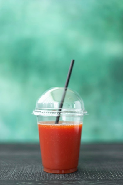 Jugo de tomate recién exprimido en una bebida para llevar de vidrio de plástico