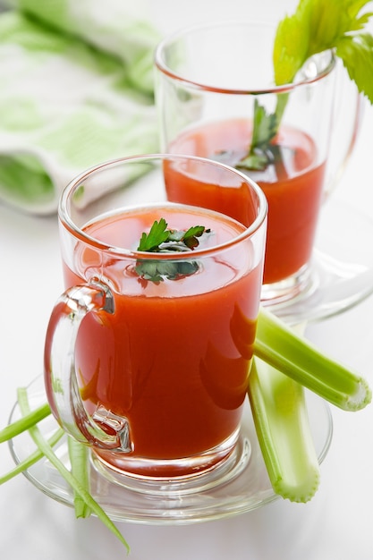 Jugo de tomate en una taza de vidrio con tallos de apio