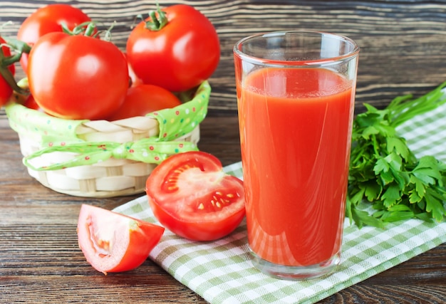 Jugo de tomate y tomates frescos en mesa de madera