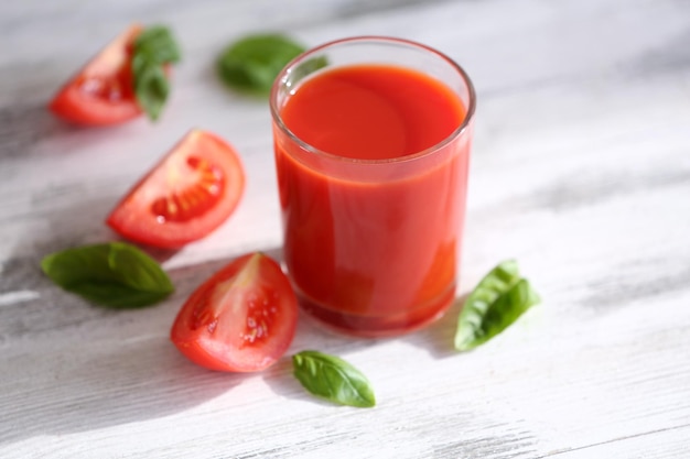 Jugo de tomate y tomates frescos en primer plano de la mesa de madera