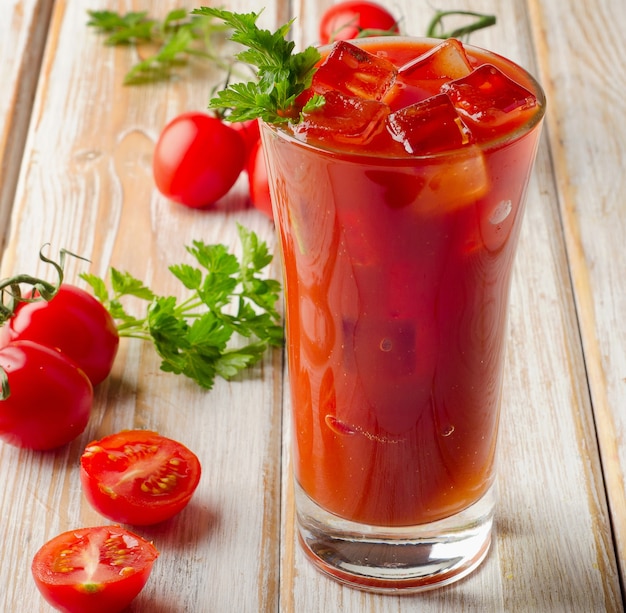 Jugo de tomate y tomates en mesa de madera