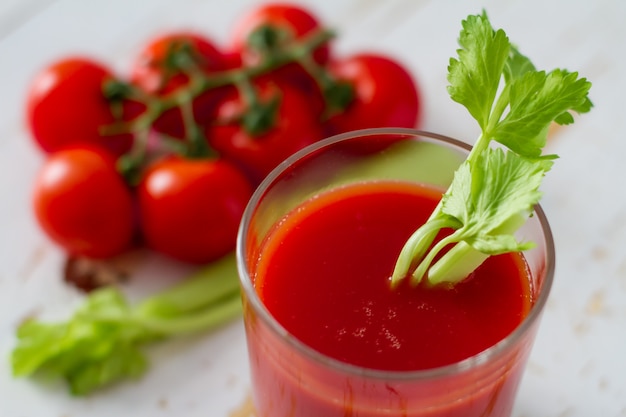 Jugo de tomate en vaso, fondo madera blanco