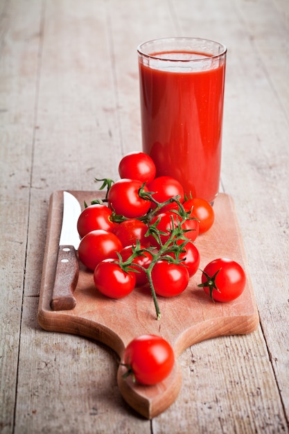 Jugo de tomate en vaso y tomates frescos.