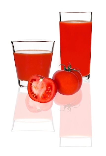 Jugo de tomate en un vaso y tomates rojos sobre un fondo blanco.