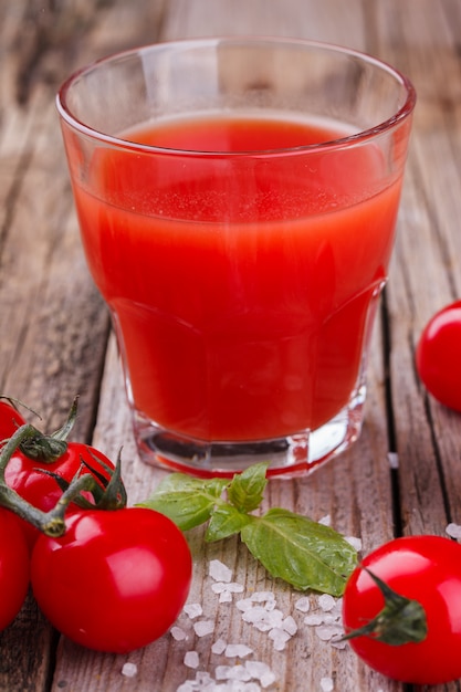 Jugo de tomate en un vaso de vidrio. Tomates y albahaca