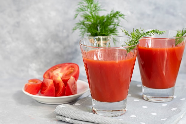 Jugo de tomate en vasos de vidrio y tomates frescos.
