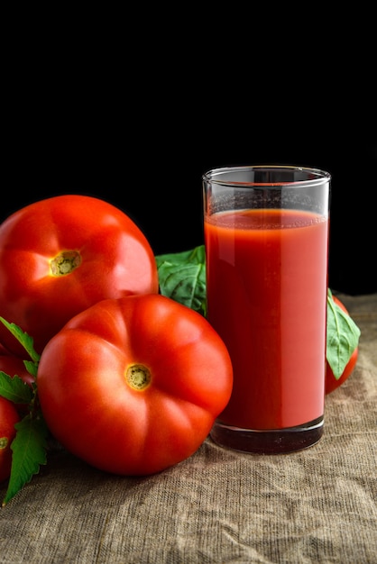 Jugo de tomate en vidrio y tomates frescos