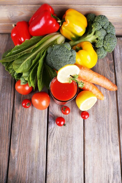 Jugo de tomate en vidrio y verduras frescas sobre fondo de madera