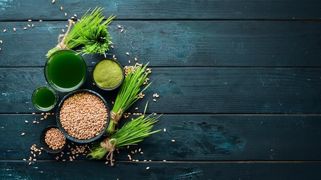 El jugo del trigo verde brotado y los granos de trigo Sobre un fondo negro Micro Green Alimentos saludables Vista superior Espacio libre para su texto