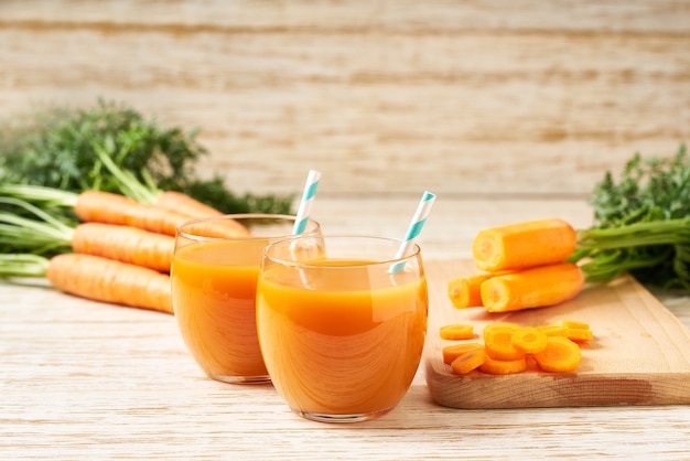 Jugo de zanahoria fresca en vasos sobre una mesa de madera blanca, enfoque selectivo. Dieta de desintoxicación saludable.