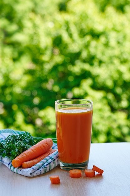 Jugo de zanahoria fresco en un vaso en la naturaleza