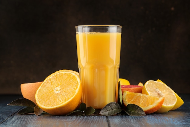 Jugos de cítricos. Jugo de naranja con frutas frescas en una mesa de madera azul. con espacio para texto.