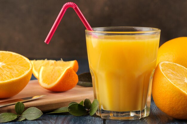 Jugos de cítricos. Jugo de naranja con naranjas frescas sobre una mesa de madera azul.