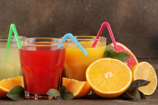 Jugos de cítricos. Limón, pomelo y jugo de naranja con frutas frescas en una mesa de madera marrón